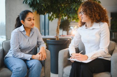 Hintli bir kadın, bir kadın psikologla danışmanlık seansında ruh sağlığı ve refahı hakkında konuşuyor.