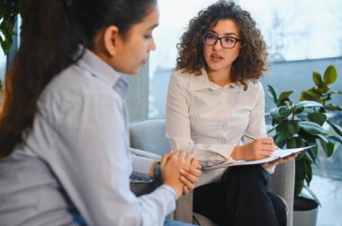 Ruh sağlığı danışmanlığı sırasında bir hastaya destek veren ve onu dinleyen kadın psikolog.