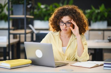 Genç kız öğrenci bilgisayarında çalışırken yorgun ve bunalmış hissediyor. İnternette öğreniyor.