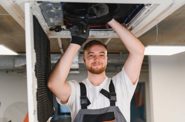 Modern bir ofiste serin hava ve konforlu iklimi sağlayan, Hvac sistemini sürdüren ve onaran profesyonel teknisyen