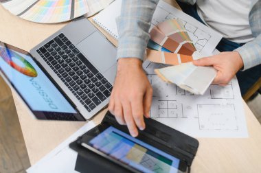 Profesyonel iç mimar mimari kat planları hazırlıyor ve yenileme projesi için belirli renk örnekleri seçiyor