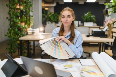 Yaratıcı bir proje üzerinde çalışan kadın tasarımcı, modern ofis ortamında palet parçalı renkler seçiyor