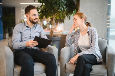 Erkek psikolog bayan müşteriyle konuşuyor. Arkadaşça bir ruh sağlığı terapisi ayarında destek ve rehberlik öneriyor.