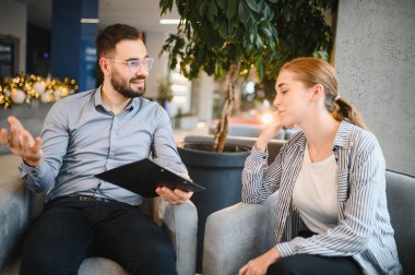 Klinikteki danışmanlık seansında erkek psikologdan profesyonel destek alan genç bir kadın.
