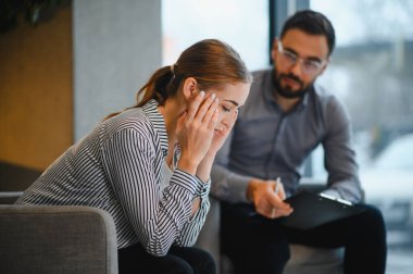 Kadın, erkek bir terapistle terapi seansında, zihinsel sağlık sorunları ve destek hakkında tartışırken sıkıntılı hissediyor.