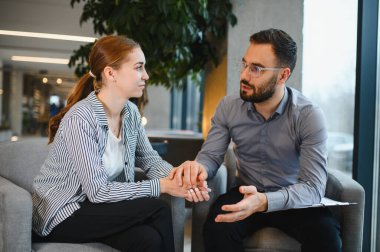 Kadın hasta, özel terapi seansı sırasında erkek psikoterapistten destek alıyor.