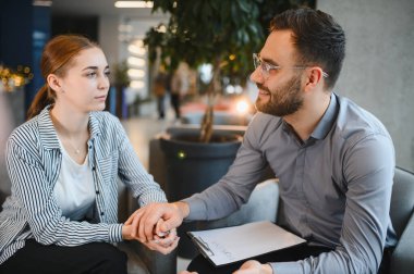 Psikolog, terapi seansı sırasında stresli genç bir kadına sempati ve destek veriyor. Ruh sağlığı ve refahı üzerine yoğunlaşıyor.