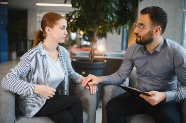 Kadın terapisti ile terapi sırasında yoğun bir konuşma yapıyor. Ruh sağlığı için destek ve tavsiye alıyor.