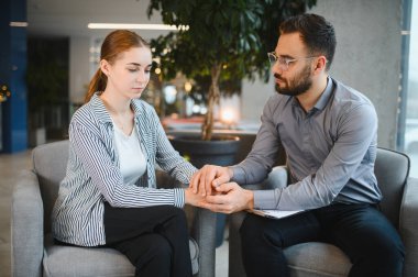 Psikolog genç bir kadını rahatlatıyor, zihinsel sağlık ve stres danışmanlığı sırasında empati ve destek öneriyor.