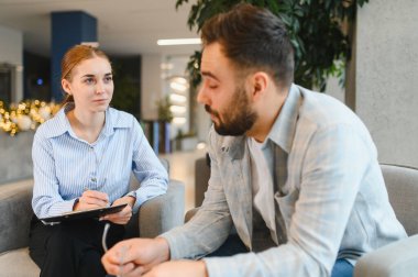 Adam profesyonel bir terapistle sorunlarını tartışıyor. Oturum sırasında aktif olarak dinleyen ve not alan kadın