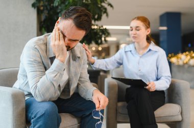 Erkek, psikoterapi seansı sırasında stresli ve depresif hissediyor. Kadın bir psikologdan destek ve empati alıyor.