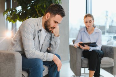 Kadın bir psikologla terapi seansında kendini stresli ve depresif hisseden bir adam profesyonel destek alıyor.