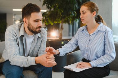 Kadın bir psikologla terapi seansında kendini stresli hisseden ve profesyonel rehberlik ve ruh sağlığı desteği alan bir adam.