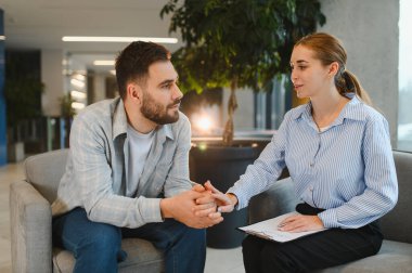 Genç adam profesyonel destek alıyor ve şefkatli bir kadın terapistle ruh sağlığı sorunlarını tartışıyor.