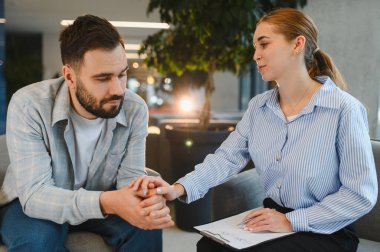 Üzgün bir adama destek ve empati sunan kadın psikolog, danışmanlık seansı sırasında akıl sağlığı sorunlarını tartışıyor.