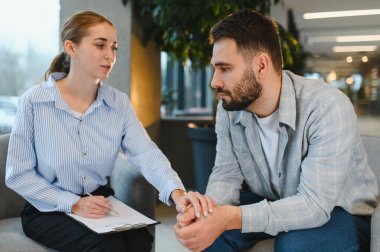 Terapi seansı sırasında stres veya depresyonla uğraşan bir adama duygusal destek veren psikolog.
