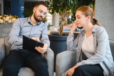 Psikolog, genç bir kadın hastayla zihinsel tedavi seansında konuşurken not alıyor.