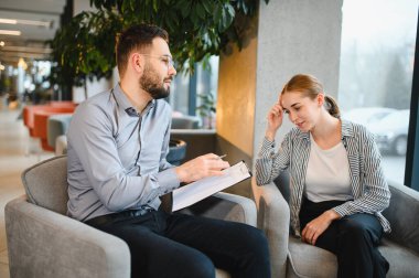 Terapi seansı sırasında sakallı bir psikologla konuşan genç bir kadın zihinsel sağlık ve stres için profesyonel yardım alıyor.