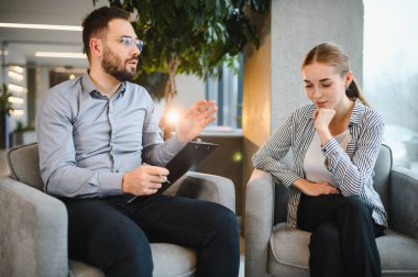 Erkek psikolog terapi seansı sırasında genç bir kadına akıl sağlığı ve refah üzerine danışmanlık yapıyor.