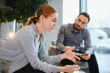 Genç bir kadın, erkek bir psikologla terapi seansı yaparken aktif olarak konuşuyor ve el kol hareketi yapıyor. Ruh sağlığı ve destek kavramları