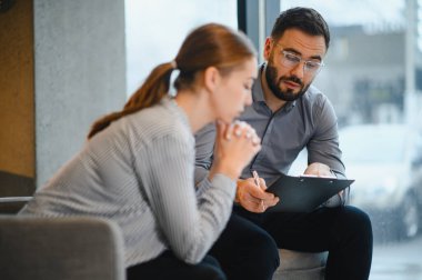 Kadın kendini sıkıntılı hissediyor ve düşüncelerini bir erkek psikologla paylaşıyor. Danışmanlık sırasında dinliyor ve notlar alıyor.