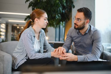 Genç bir kadın erkek bir terapistle oturuyor. Rahatlatıcı destek öneriyor. Ruh sağlığı ve duygusal sağlığa odaklanıyor.