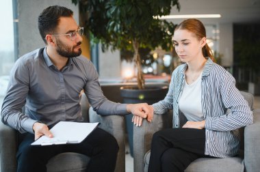 Bir erkek psikologdan destek ve danışmanlık alan genç bir kadın bireysel terapi seansı sırasında ruh sağlığı sorunlarını tartışıyor.