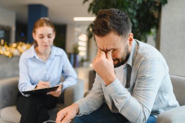 Erkek gözlerini kapatıyor, kadın bir psikologla danışmanlık seansı yapıyor ve ona destek oluyor.