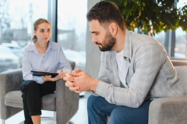 Depresyonda ve stresli hisseden bir adam, ruh sağlığı destek seansı sırasında bir psikologla sorunları paylaşıyor.