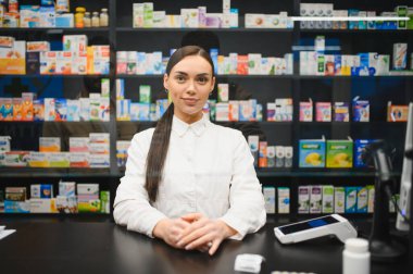 Eczanenin tezgahında duran kadın eczacı, profesyonel sağlık hizmeti ve tıbbi ürünler sunuyor.