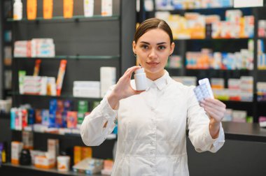 Modern bir eczanede farklı ilaç türleri sunan bir eczacı. Sağlık, sağlık ve mesleki hizmete odaklanın.