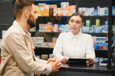 Eczacı kadınlar, modern bir eczanenin tezgahında çalışan bir erkeğe profesyonel danışmanlık yapıyorlar. Sağlık ve hizmet kavramı