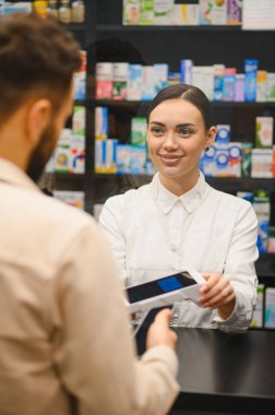Eczacının elinde ödeme terminali var. Müşteri eczanede ücretsiz ödeme yapıyor. Sağlık hizmetleri perakende ve modern hizmet kavramı