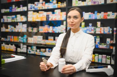 Modern bir eczanenin tezgahında duran eczacı elinde ilaç paketi ve beyaz bir şişe ile sağlık hizmetlerini temsil ediyor.
