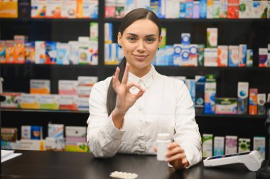 Eczane tezgahında elinde ilaç şişesi olan genç bir kadın eczacı.