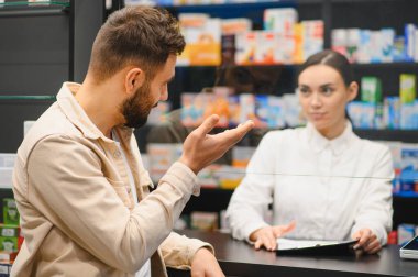 Erkek, kadın eczacıya tıp, sağlık ürünleri ya da modern bir eczanede olmak hakkında danışır.