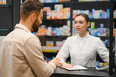 Eczacı, eczanede sağlık hizmetleri ve reçete hizmetleri için erkek müşteriyle konuşuyor.