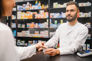 Bir eczacı modern bir eczanede bir müşteriye bir şişe ilaç veriyor.