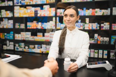 Tezgahta duran eczacı modern eczanedeki bir müşteriye ilaç veriyor. Sağlık hizmeti ve konsültasyon sağlama