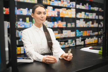 Tezgahta duran eczacı, elinde ilaç şişeleri ve su toplayan paketler, profesyonel sağlık hizmeti sunuyor.