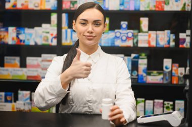 Elinde ilaç şişesi olan gülümseyen kadın eczacı müşterilere kaliteli hizmet konusunda güven veriyor.