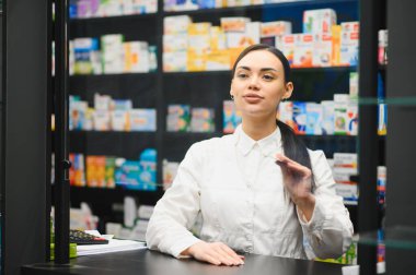 Eczacı modern eczanedeki bir müşteriye ilaçları açıklıyor. Perakende eczane ortamında çalışan sağlık uzmanı