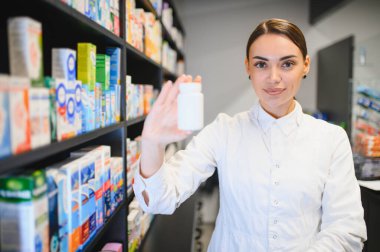 Modern bir eczanede elinde boş bir ilaç şişesiyle duran eczacı, sağlık hizmeti ve tıbbi tavsiyelerde bulunuyor.