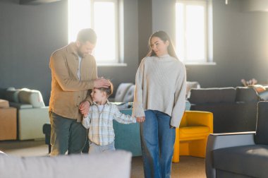 Ebeveynler ve oğulları mobilya alışverişini seviyorlar, yeni evleri için parlak bir galeride seçenekler arıyorlar.