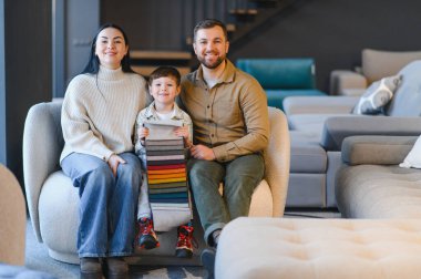 Mutlu aile, ebeveynler ve çocuklar, bir kanepede oturuyor, iç tasarım seçimleri için kumaş örnekleri tutuyor.