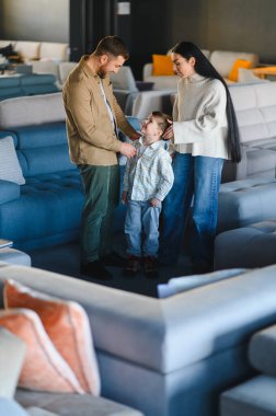 Ebeveynler ve çocuklar yeni bir kanepe seçiyorlar, gelecekteki ev dekorasyonu için karar veriyorlar. Aile hayatı perakendeciliğin tadını çıkarıyor