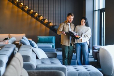 Mutlu çift, modern bir perakende galerisinde kanepe kumaşı için döşeme kumaşı seçiyor. Yeni bir ev tasarımı planlıyorlar.