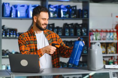 Otomobil parçaları işçisi kayganlaştırıcı şişedeki barkodu tarıyor, envanteri yönetiyor ve satışları bir dizüstü bilgisayar ve tarayıcı ile işliyor.