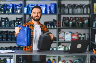 Kendine güvenen sakallı satıcı bir araba parçası dükkanında motor yağı ve kayganlaştırıcı tavsiye ederek otomotiv ürünü seçimi sunuyor.