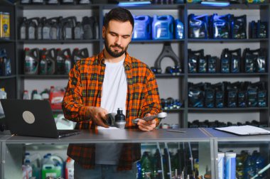 Arka planda çeşitli kayganlaştırıcıları ve araçları olan bir oto tamir atölyesinde araba yedek parçalarının tutulması ve incelenmesi